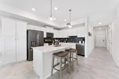 a kitchen with white cabinets and a large island with bar stools at Brand New Lakeview Storey Lake Resort Disney 3121-103 in Kissimmee