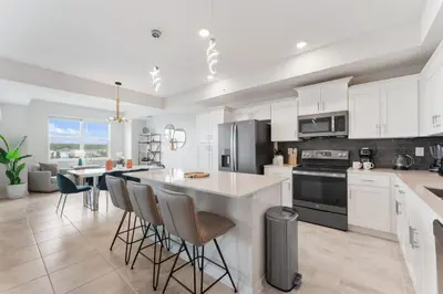 a kitchen with white cabinets and a kitchen island with bar chairs at Modern Storey Lake Resort Disney Orlando 3171-302 in Kissimmee