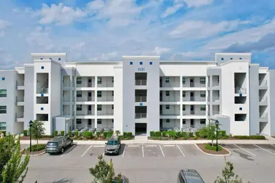 a large white apartment building with a parking lot at Modern Storey Lake Resort Disney Orlando 3121-108 in Kissimmee