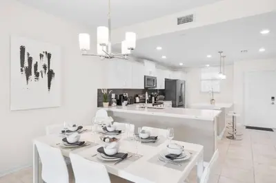 a white kitchen with a white table and chairs at Modern Storey Lake Resort Disney Orlando 3141-105 in Kissimmee