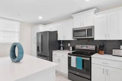 a kitchen with white cabinets and a black appliance at Modern Storey Lake Resort Disney Orlando 3180-104 in Kissimmee