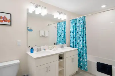 a bathroom with a sink and a blue shower curtain at Modern Storey Lake Resort Disney Orlando 3180-104 in Kissimmee