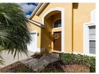 a yellow house with a palm tree in front of it at Make your dreams really come true in Kissimmee