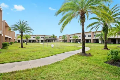 a park with palm trees in front of a building at MAGIC VILLAGE - Near Disney - 4BDR in Orlando