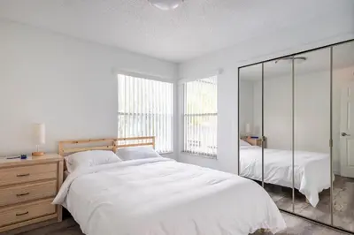 a white bedroom with a bed and a mirror at The Villa of Somerset in Kissimmee