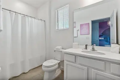 a white bathroom with a toilet and a sink at Beautiful 12Bed11.5Bath House At Bella Vida in Kissimmee