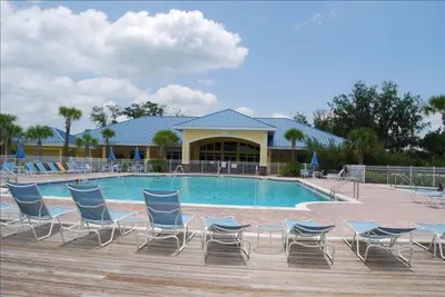 a swimming pool with chairs and a building at Smart home near Disney world, Silver Spurs Arena in Kissimmee