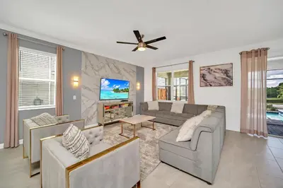 a living room with a couch and a tv at Perfect 9 Bed 5 Bath Home/Games room/ Private pool in Kissimmee