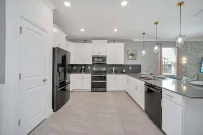 a large kitchen with white cabinets and black appliances at Perfect 9 Bed 5 Bath Home/Games room/ Private pool in Kissimmee