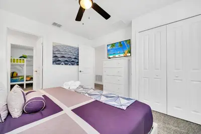 a bedroom with a purple bed and a ceiling fan at Brand New 6BD, Gameroom / Movie Theater And Pool in Kissimmee