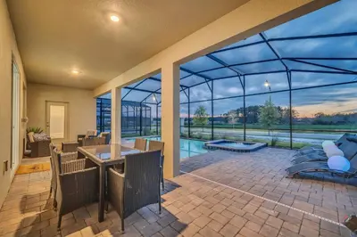 a large glass house with a patio with a swimming pool at Brand New 6BD, Gameroom / Movie Theater And Pool in Kissimmee