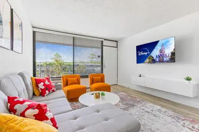 a living room with a white couch and orange chairs at 15 Mins from Disney World l Theme Room l Pool in Kissimmee