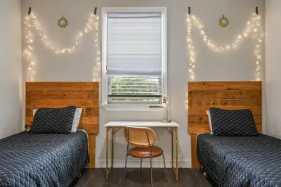 a bedroom with two beds and a table and a window at Pool Table, BBQ, Walking Distance to Local Gems in Orlando