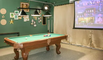 a room with a pool table in front of a screen at Pool Table, BBQ, Walking Distance to Local Gems in Orlando