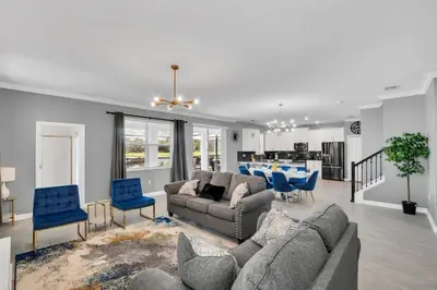 a living room with a couch and chairs and a kitchen at Mickey's Retreat /Pool With Water Slide/ Game Room in Kissimmee