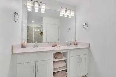 a white bathroom with a sink and a mirror at Stylish 2-Bed Condo With Resort Amenities/Patio in Kissimmee
