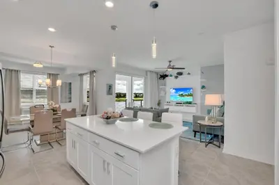 a kitchen and dining room with white cabinets and a table at Stylish 2-Bed Condo With Resort Amenities/Patio in Kissimmee