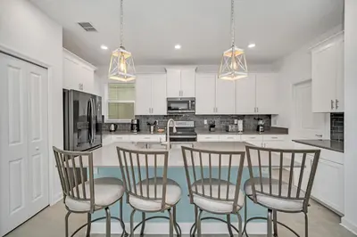 a kitchen with white cabinets and a table with four chairs at Amazing Brand New 5BD, Resort Home/Games Room/Pool in Kissimmee