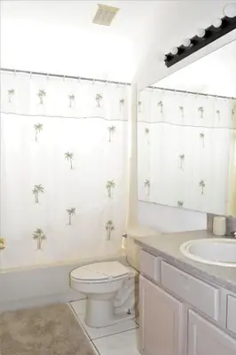 a bathroom with a toilet and a sink with palm trees on the wall at 6 bed property - Indian Creek in Kissimmee