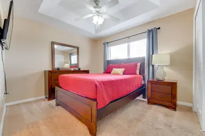 a bedroom with a bed and a dresser and a mirror at 4 Mi to Disney! Family Townhome with Pool Access in Kissimmee