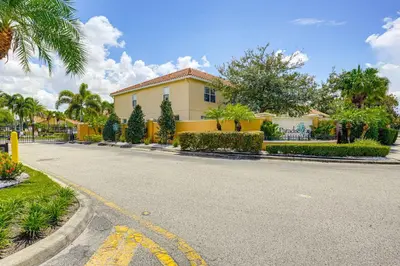 a street with a yellow house on a road at 4 Mi to Disney! Family Townhome with Pool Access in Kissimmee