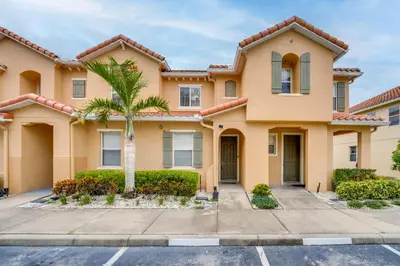 a house with a palm tree in a parking lot at 4 Mi to Disney! Family Townhome with Pool Access in Kissimmee