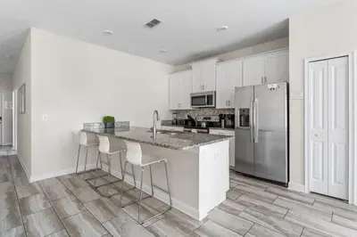 a white kitchen with a counter and a refrigerator at 5BR 10 minutes from Disney Springs SL4800 in Kissimmee
