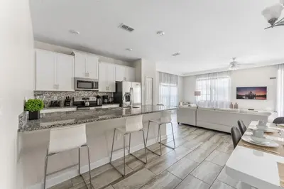 a kitchen with white cabinets and a table and chairs at 5BR 10 minutes from Disney Springs SL4800 in Kissimmee