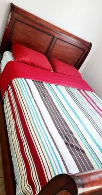 a bed with a wooden head board and red pillows at Ava Lea's Falls in Orlando