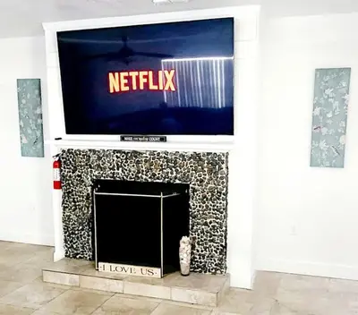 a television on top of a fireplace with a cat sitting under it at Ava Lea's Falls in Orlando
