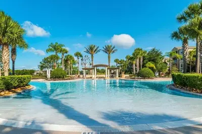 a large swimming pool with palm trees in a resort at 3Q no Windsor Hills | Perto da Disney + Parque in Orlando