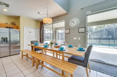 a dining room with a table and a clock on the wall at 5 Mi to Disney Ideal Family Getaway with Theater! in Kissimmee
