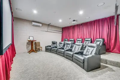 a movie room with leather chairs and a red curtain at 5 Mi to Disney Ideal Family Getaway with Theater! in Kissimmee