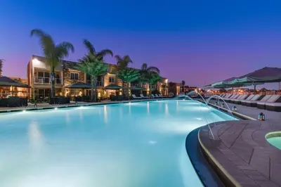 a large swimming pool with palm trees and buildings at Magic Village Yards Trademark Collection by Wyndham in Orlando