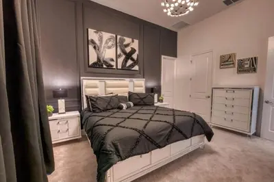 a bedroom with a black and white bed and a chandelier at Experience Luxury in Your 11 En-Suites Mansion in Orlando