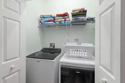 a small laundry room with a stove and towels at Single-Level Home w Heated Pool & 9MI to Disney in Orlando