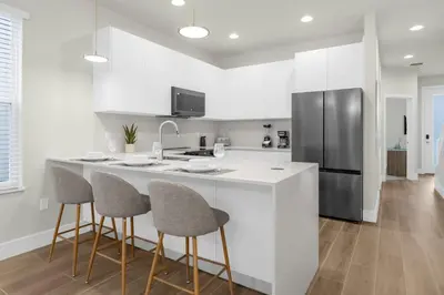 a kitchen with a counter with stools and a refrigerator at Upstay - Modern Family Townhome with Pool in Orlando
