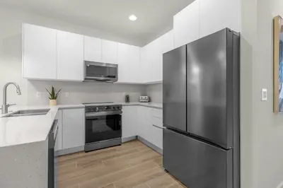 a kitchen with white cabinets and a stainless steel refrigerator at Upstay - Modern Family Townhome with Pool in Orlando