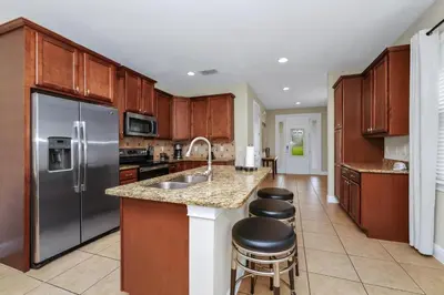 a kitchen with wooden cabinets and a stainless steel refrigerator at Charming Home Near Disney With Private Pool, Game Room And Waterpark & Resort Access At Encore Resorts Reunion - 410No in Kissimmee