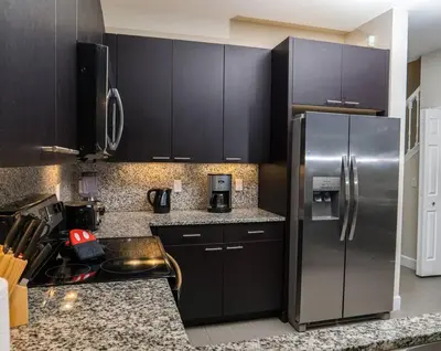 a kitchen with black cabinets and a stainless steel refrigerator at Clermont Family Townhouse Pool & Arcade near Disney in Orlando