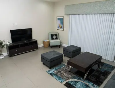 a living room with a flat screen tv and stools at Clermont Family Townhouse Pool & Arcade near Disney in Orlando