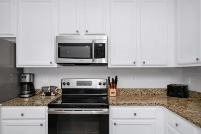 a kitchen with white cabinets and a stove and a microwave at Glorious Home Near Disney With Game Room, Themed Rooms, Waterpark & Resort Access At Encore Resorts Reunion - 7643Wi in Kissimmee
