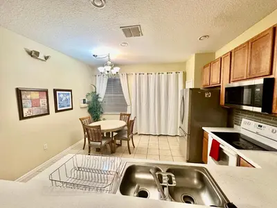 a kitchen with a sink and a table with a dining room at Grand Luxury 3BR Townhouse Near Disney Parks in Kissimmee