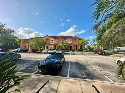 a black car parked in a parking lot in front of a house at Grand Luxury 3BR Townhouse Near Disney Parks in Kissimmee