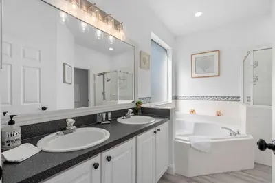 a white bathroom with two sinks and a bath tub at Tropical 7BR Heated Pool Pet Friendly Disney in Kissimmee