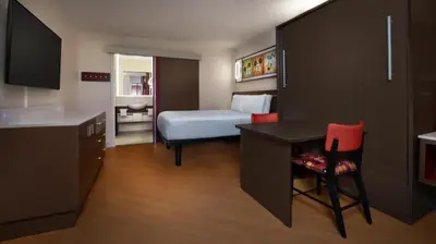 a hotel room with a bed and a desk and a bedroom at Disney's All-Star Music Resort in Orlando