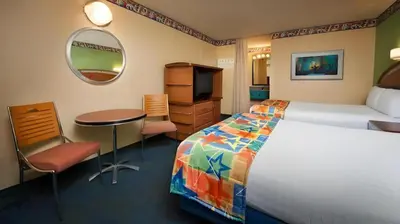a hotel room with a bed and a table and a mirror at Disney's All-Star Music Resort in Orlando