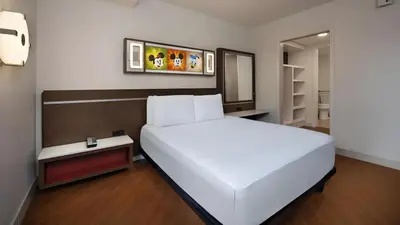 a bedroom with a large white bed and a mirror at Disney's All-Star Music Resort in Orlando