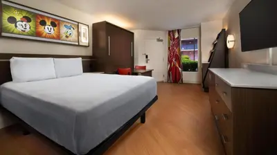a bedroom with a large white bed and a kitchen at Disney's All-Star Sports Resort in Orlando