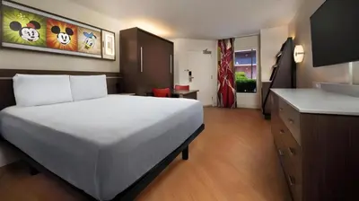 a bedroom with a large white bed and a kitchen at Disney's All-Star Sports Resort in Orlando